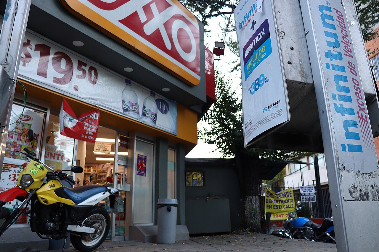 Corner of an OXXO convenience store in Mexico City with a motorcycle parked outside and a prepaid top-up sign on a pole